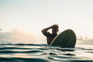 man holding white surfboard