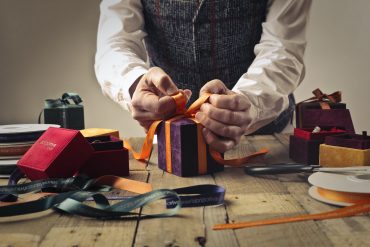 person tying ribbon on purple gift box